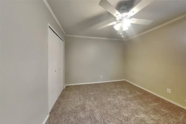 an empty room with a chandelier fan and windows