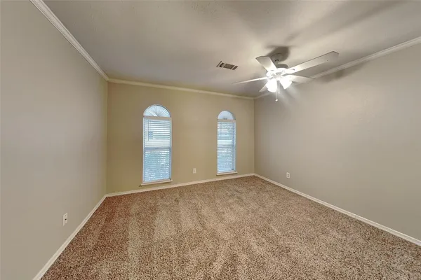 an empty room with chandelier fan and windows