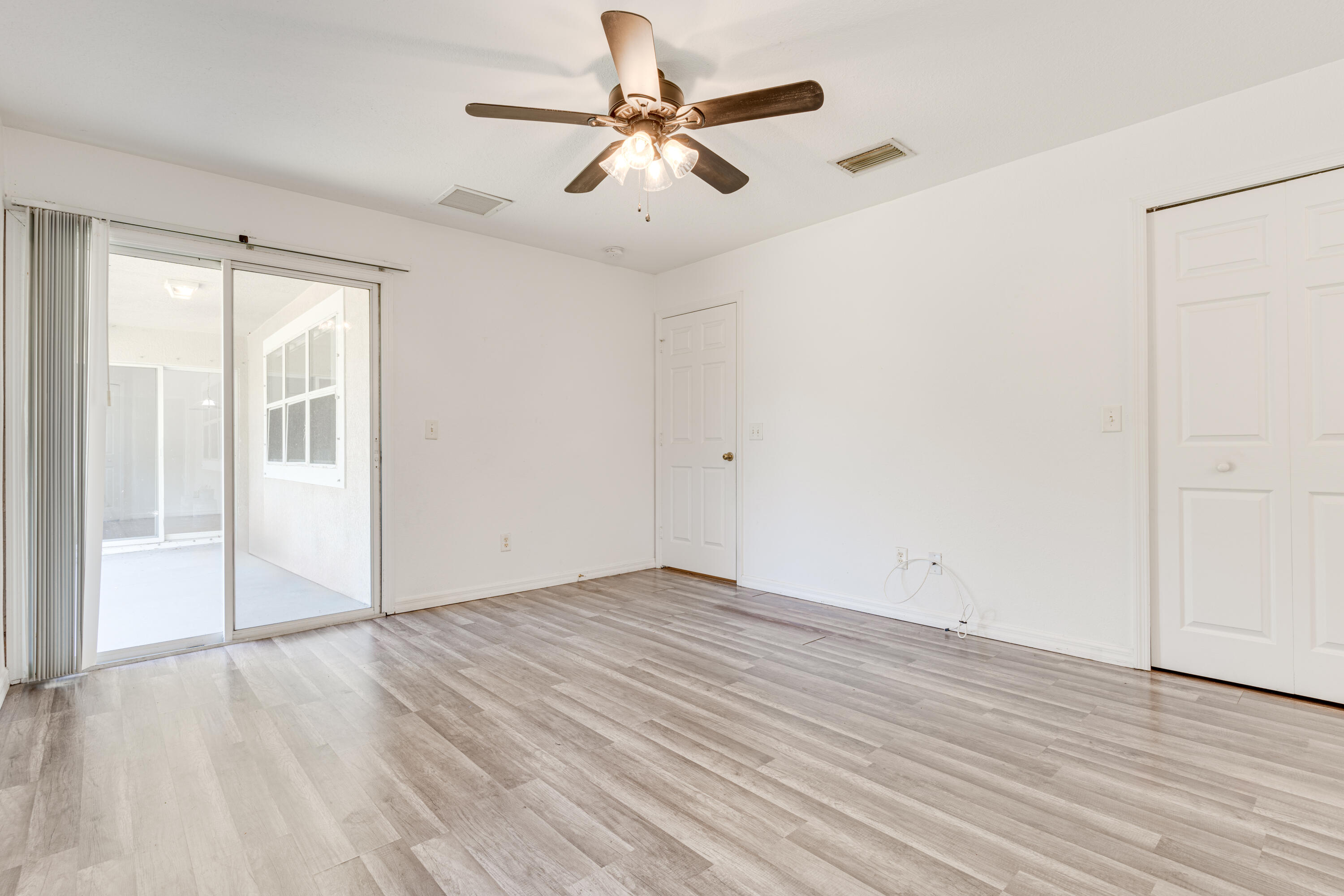 500 Topeka Road Southwest Palm Bay, FL 32908 - Photo 10 of 12 an empty room with wooden floor fan and windows