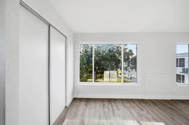 an empty room with wooden floor and windows