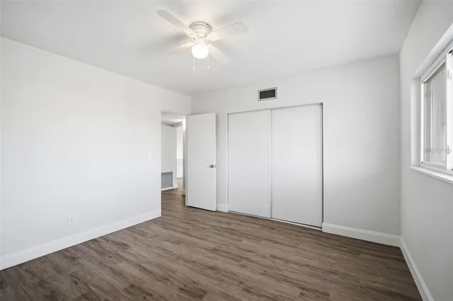 an empty room with wooden floor and window