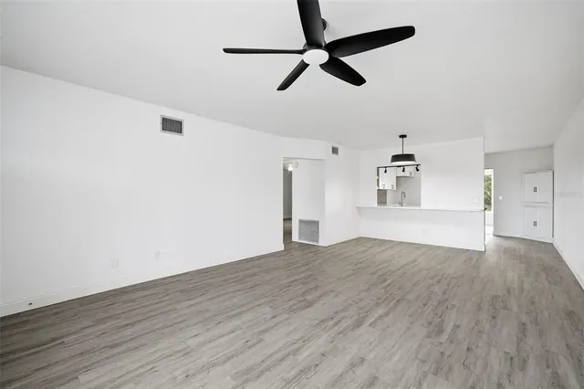 a view of empty room with wooden floor and ceiling fan