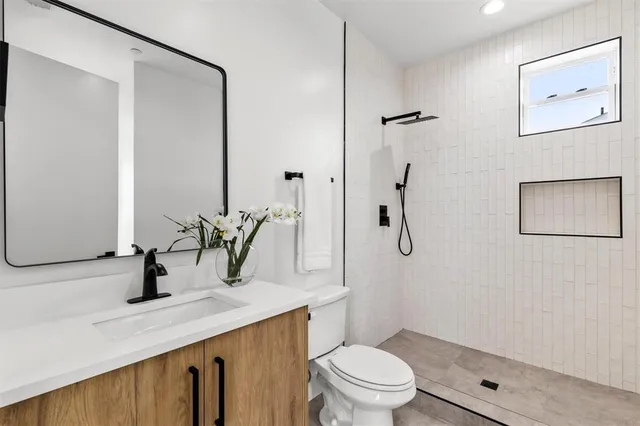 a bathroom with a granite countertop sink a toilet and shower
