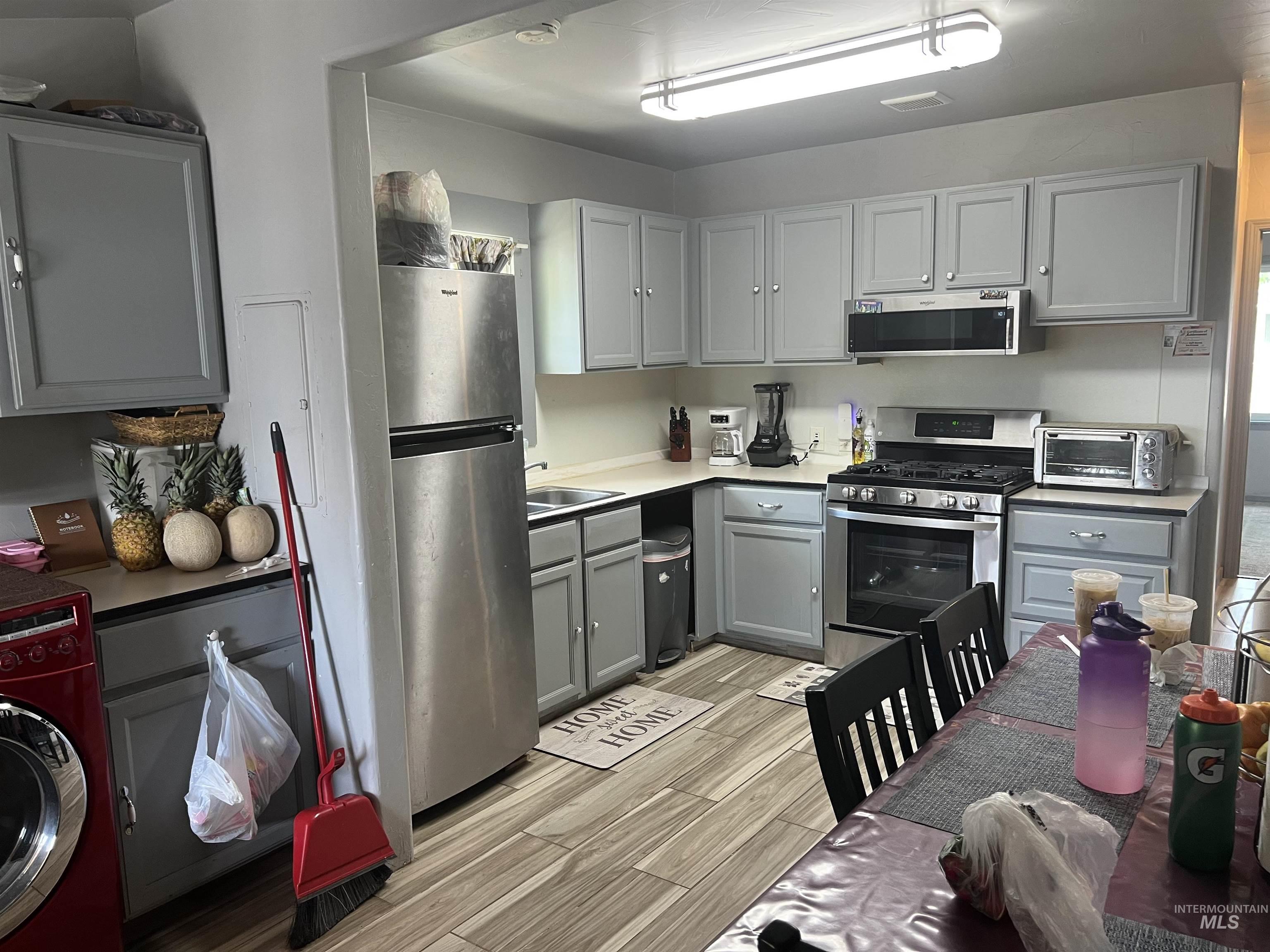 121 North 1st Street Nyssa, OR 97913 - Photo 7 of 20 Kitchen featuring wood-finish flooring, stainless steel appliances, light gray cabinetry with brushed nickel hardware, a built-in microwave, and a gas range
