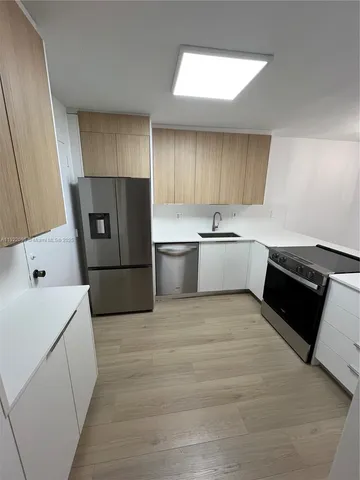 a large white kitchen with a sink stainless steel appliances and cabinets
