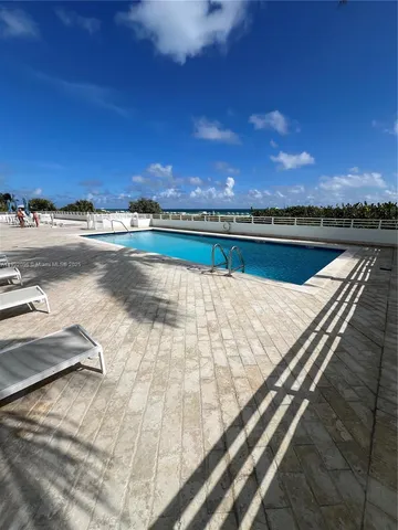 a view of swimming pool with outdoor seating and yard in back