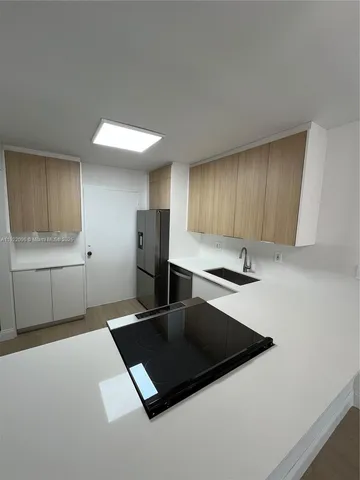 a kitchen with stainless steel appliances a sink a stove a refrigerator a microwave and cabinets