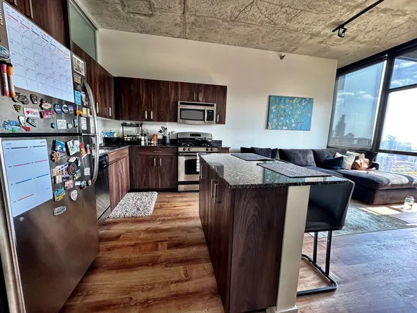 a living room with stainless steel appliances granite countertop furniture a fireplace a flat screen tv and a kitchen view