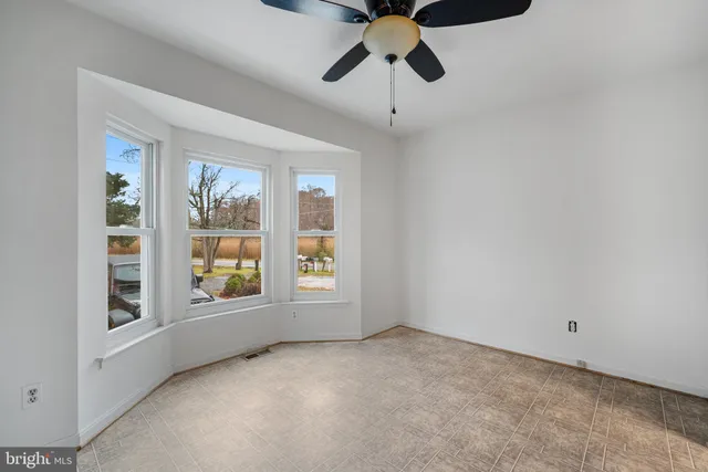 an empty room with windows and ceiling fan