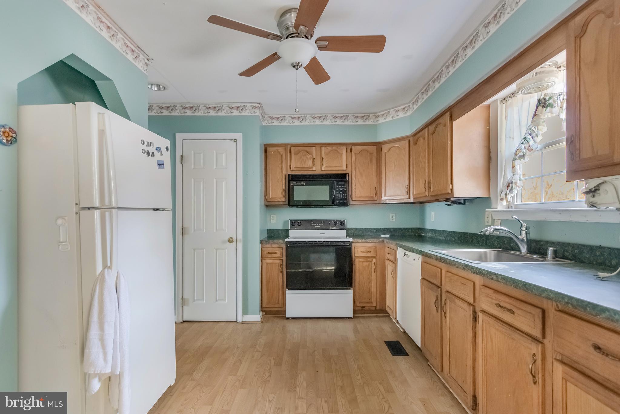 1104 Saffron Way Owings, MD 20736 - Photo 9 of 26 a kitchen with stainless steel appliances granite countertop a refrigerator a sink a stove a microwave and island with wooden cabinets