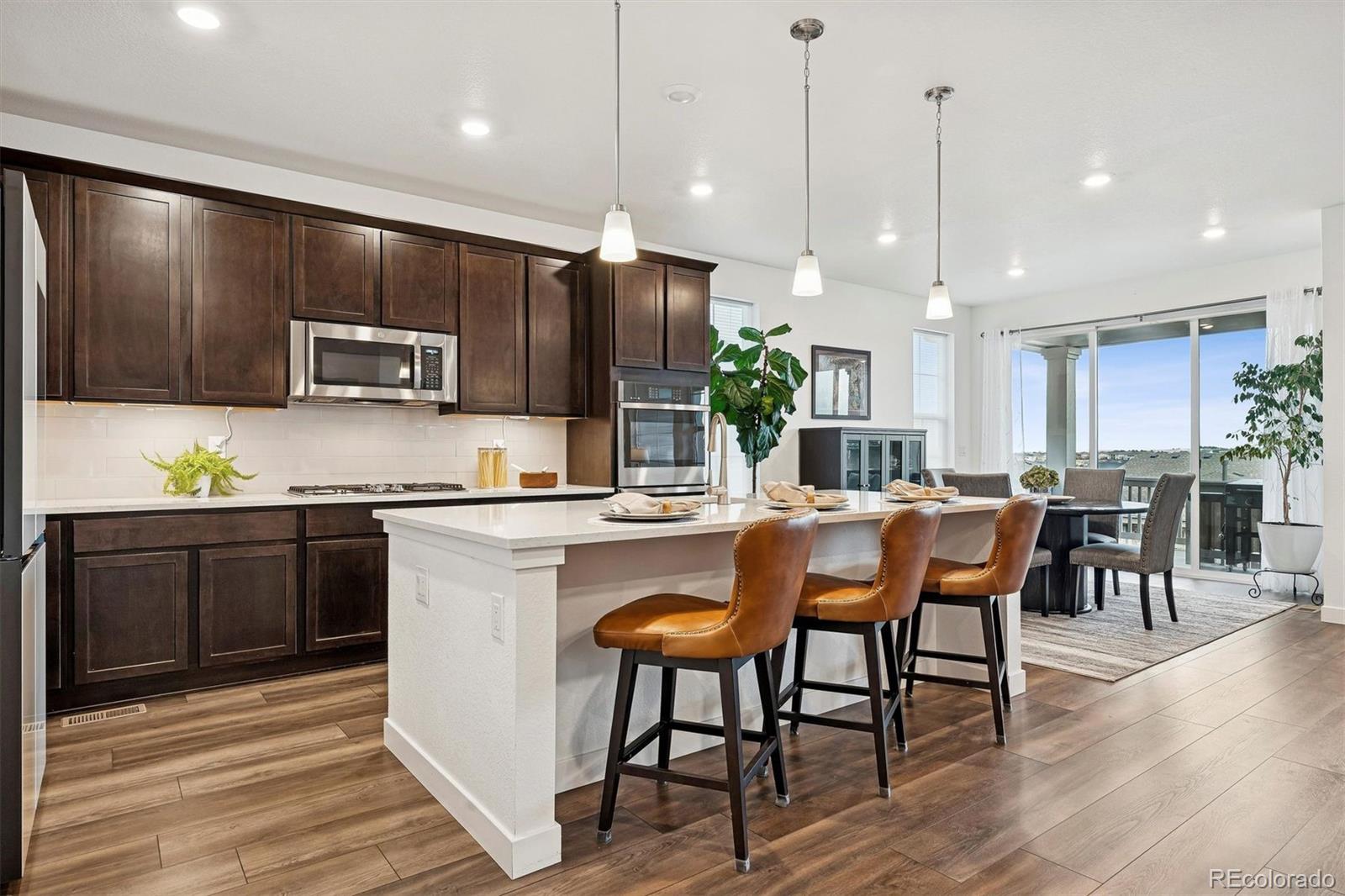 8500 South Riviera Court Aurora, CO 80016 - Photo 6 of 35 a kitchen with stainless steel appliances granite countertop a refrigerator a stove a sink a dining table and chairs with wooden floor