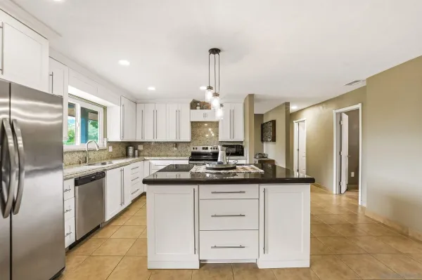 a kitchen with kitchen island granite countertop a sink and refrigerator