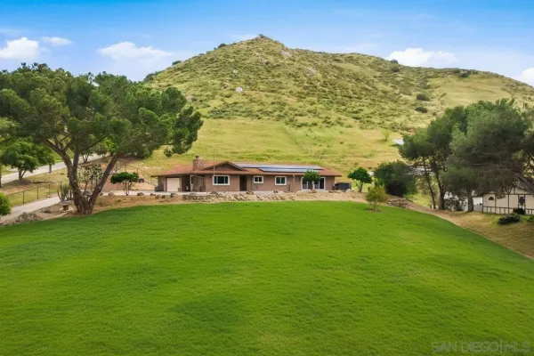a view of a big house with a big yard and large trees