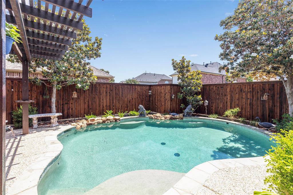 1217 Windmere Way Allen, TX 75013 - Photo 4 of 38 Surrounded by lush landscaping and custom stonework, the lagoon-style pool transforms the backyard into a peaceful escape designed for relaxing and entertaining alike.