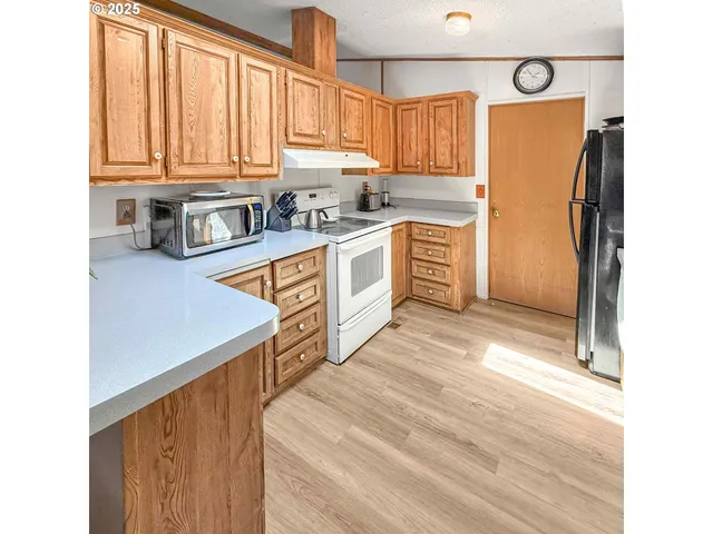 a kitchen with stainless steel appliances granite countertop a refrigerator a sink dishwasher and wooden cabinets with wooden floor