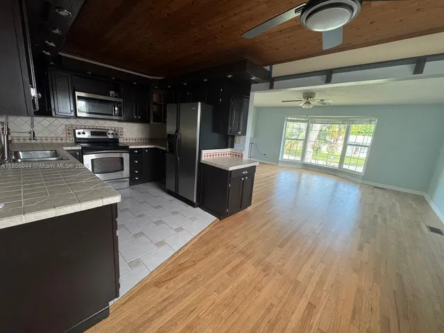a kitchen with stainless steel appliances granite countertop a sink a stove and a wooden floors
