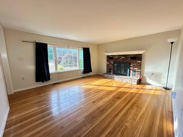 an empty room with wooden floor fireplace and windows