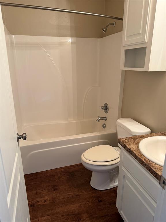520 Big Red Circle Haughton, LA 71037 - Photo 14 of 25 Bathroom featuring a white integrated tub and shower unit, a toilet, a vanity with a white basin and patterned countertop, wood-finish flooring, and white cabinetry