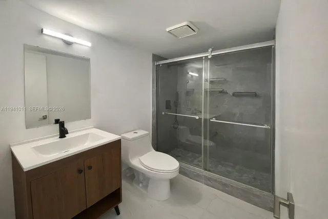 a bathroom with a shower sink mirror and toilet