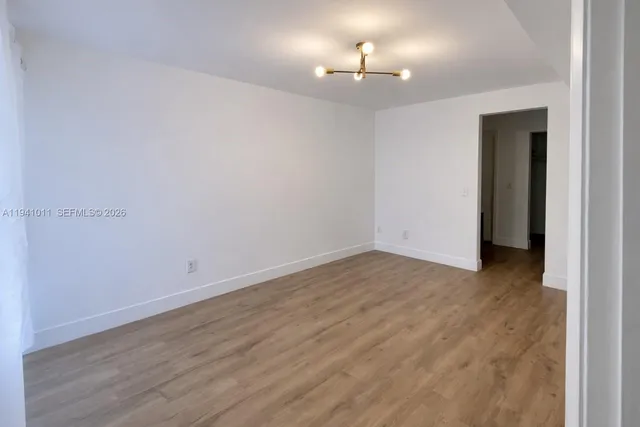 a view of an empty room with a chandelier fan