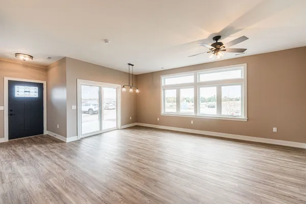 a view of an empty room with a window and wooden floor