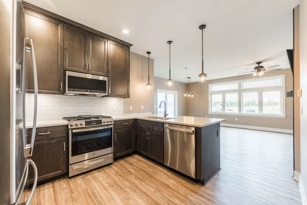 a kitchen with stainless steel appliances granite countertop a stove a sink and a microwave