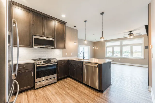 a kitchen with stainless steel appliances granite countertop a stove a sink and a microwave