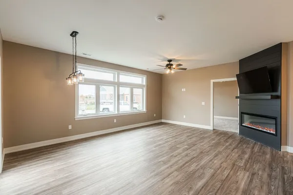 an empty room with wooden floor cabinet and windows