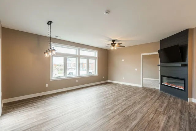 an empty room with wooden floor cabinet and windows