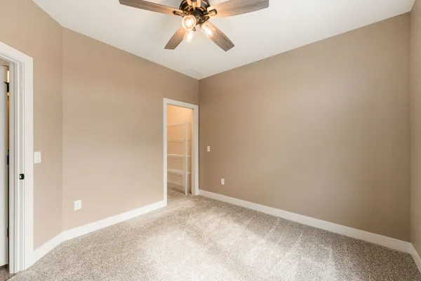 a view of an empty room and chandelier fan