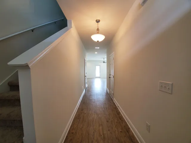 a view of a hallway with wooden floor and a bathroom