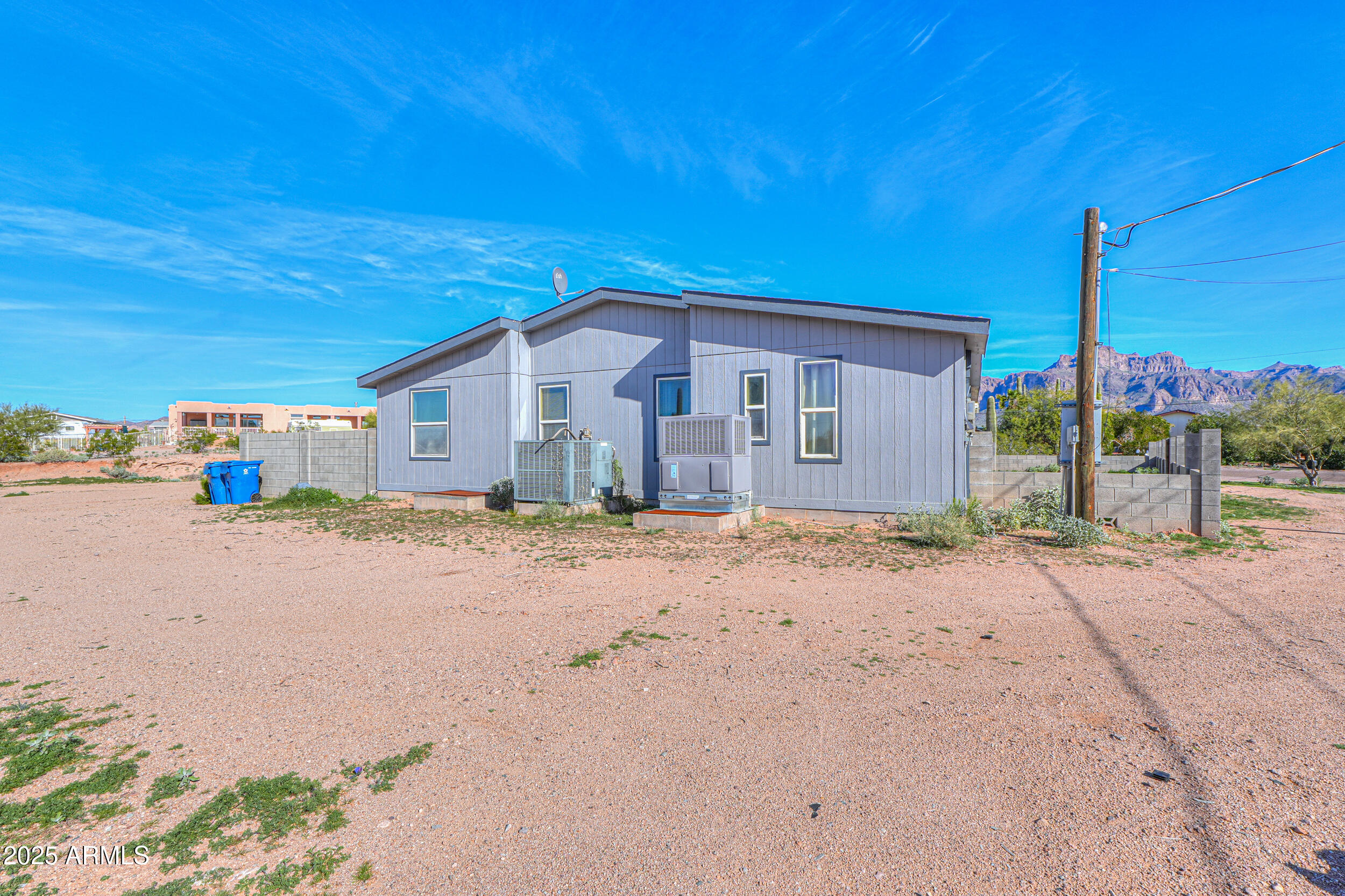 176 North Acacia Road Apache Junction, AZ 85119 - Photo 58 of 65 a front view of a house with a dirt yard and parking space