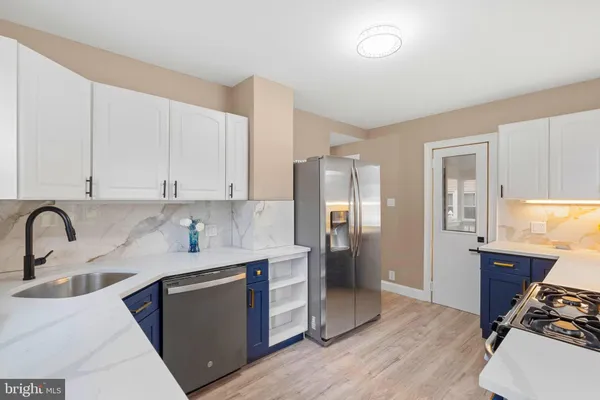 a kitchen with stainless steel appliances granite countertop a refrigerator sink and white cabinets