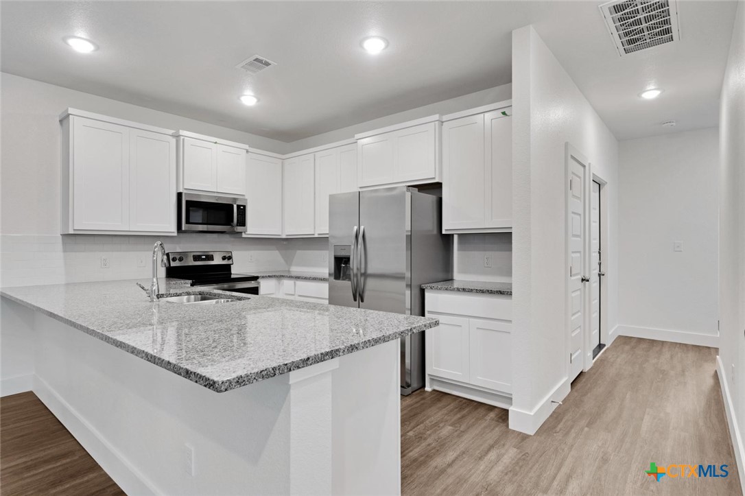 1924 Royal Loop Belton, TX 76513 - Photo 2 of 15 a kitchen with a refrigerator a microwave a sink and white cabinets