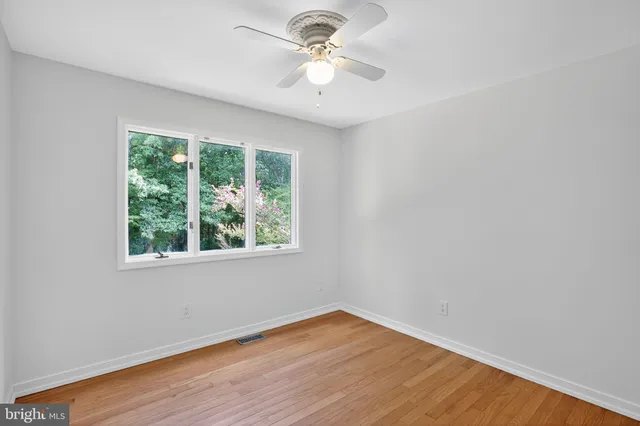 a big room with wooden floor a chandelier fan and windows