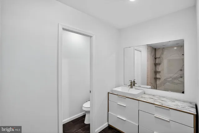 a bathroom with a granite countertop sink a toilet and a mirror