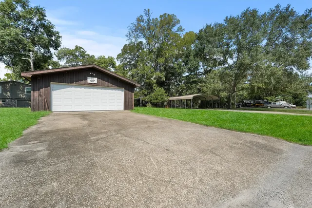 a view of a house with a yard and large trees