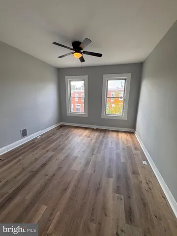 a view of empty room with wooden floor and fan