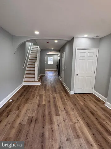 a view of an empty room with wooden floor and stairs