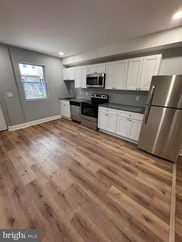 a kitchen with granite countertop a refrigerator sink and cabinets