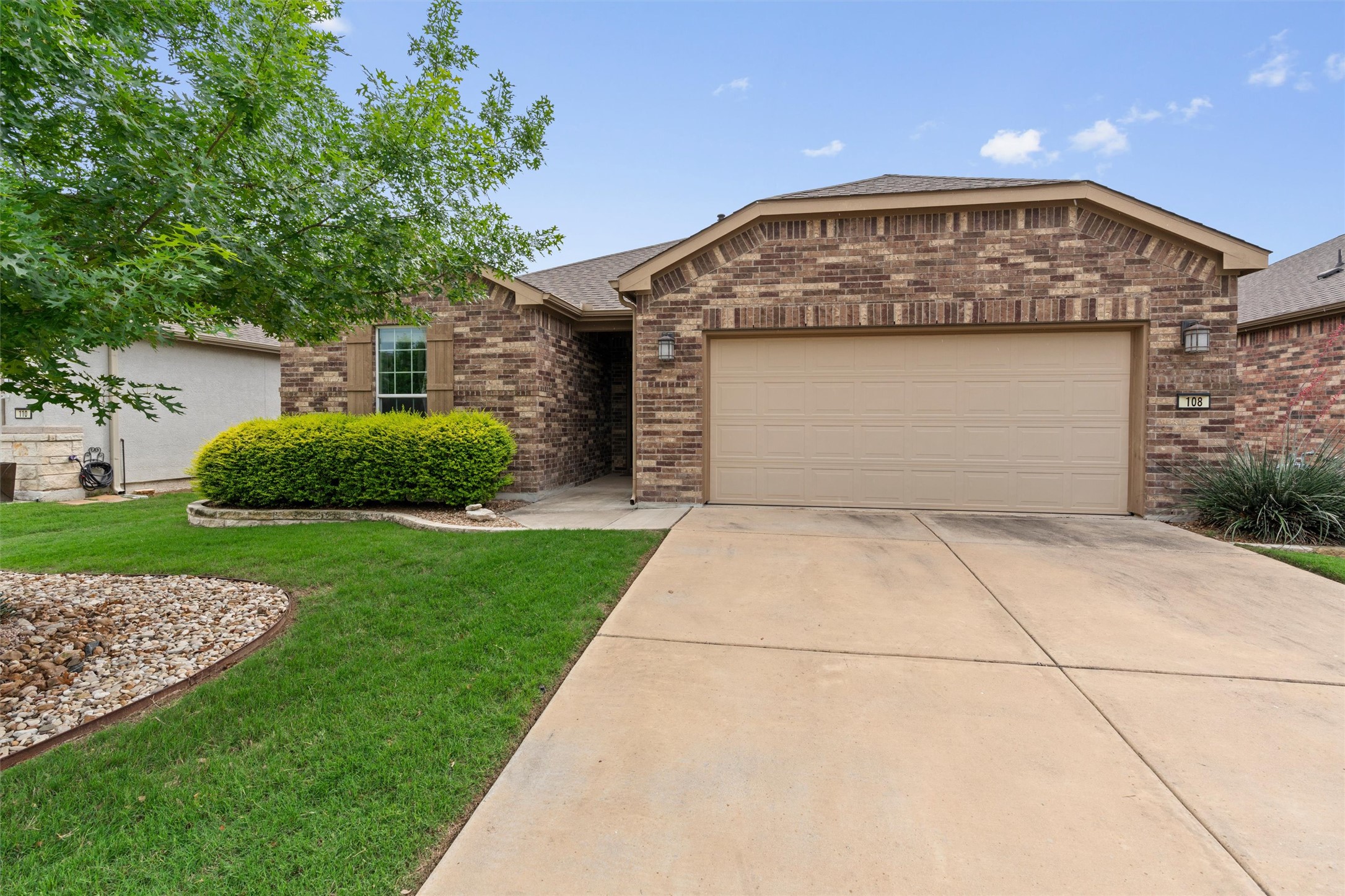 The property features a brick exterior, a two-car garage, a concrete driveway, and a well-maintained lawn with landscaping
