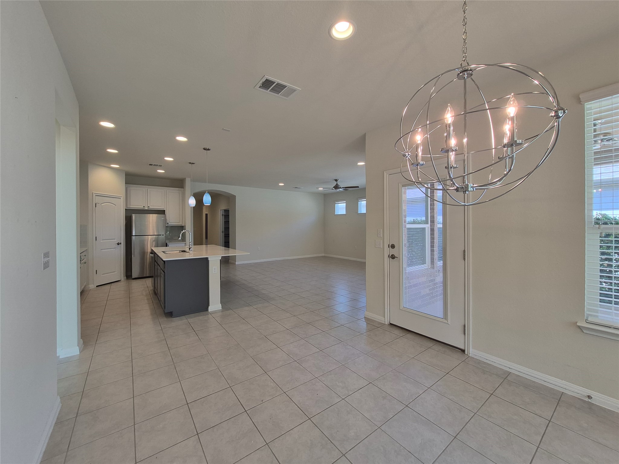 108 Calhoun Lane Georgetown, TX 78633 - Photo 27 of 27 Dual tone kitchen featuring arched walkways, open floor plan, a ceiling fan, a center island with sink, and two tone color scheme
