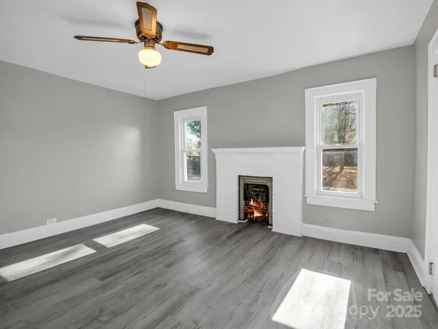 an empty room with windows and fireplace