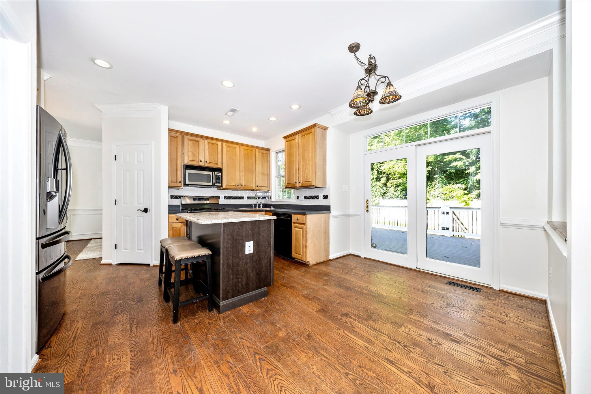 803 Apache Court Frederick, MD 21701 - Photo 12 of 46 a kitchen with kitchen island granite countertop wooden floors stainless steel appliances and dining table