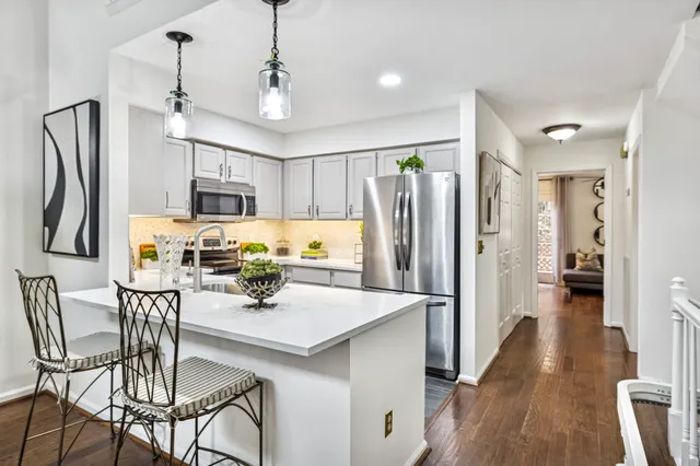 a kitchen with stainless steel appliances a dining table chairs refrigerator and microwave