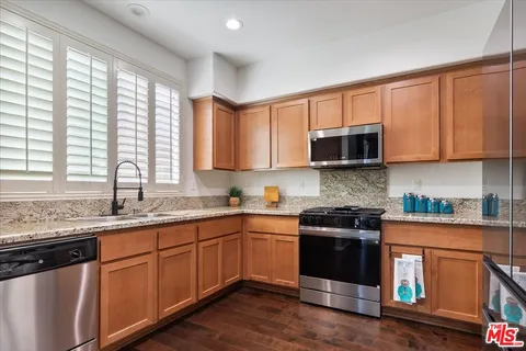 a kitchen with stainless steel appliances granite countertop wooden cabinets a sink and a stove