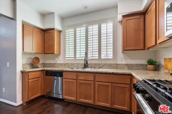 a kitchen with granite countertop stainless steel appliances a sink stove and cabinets