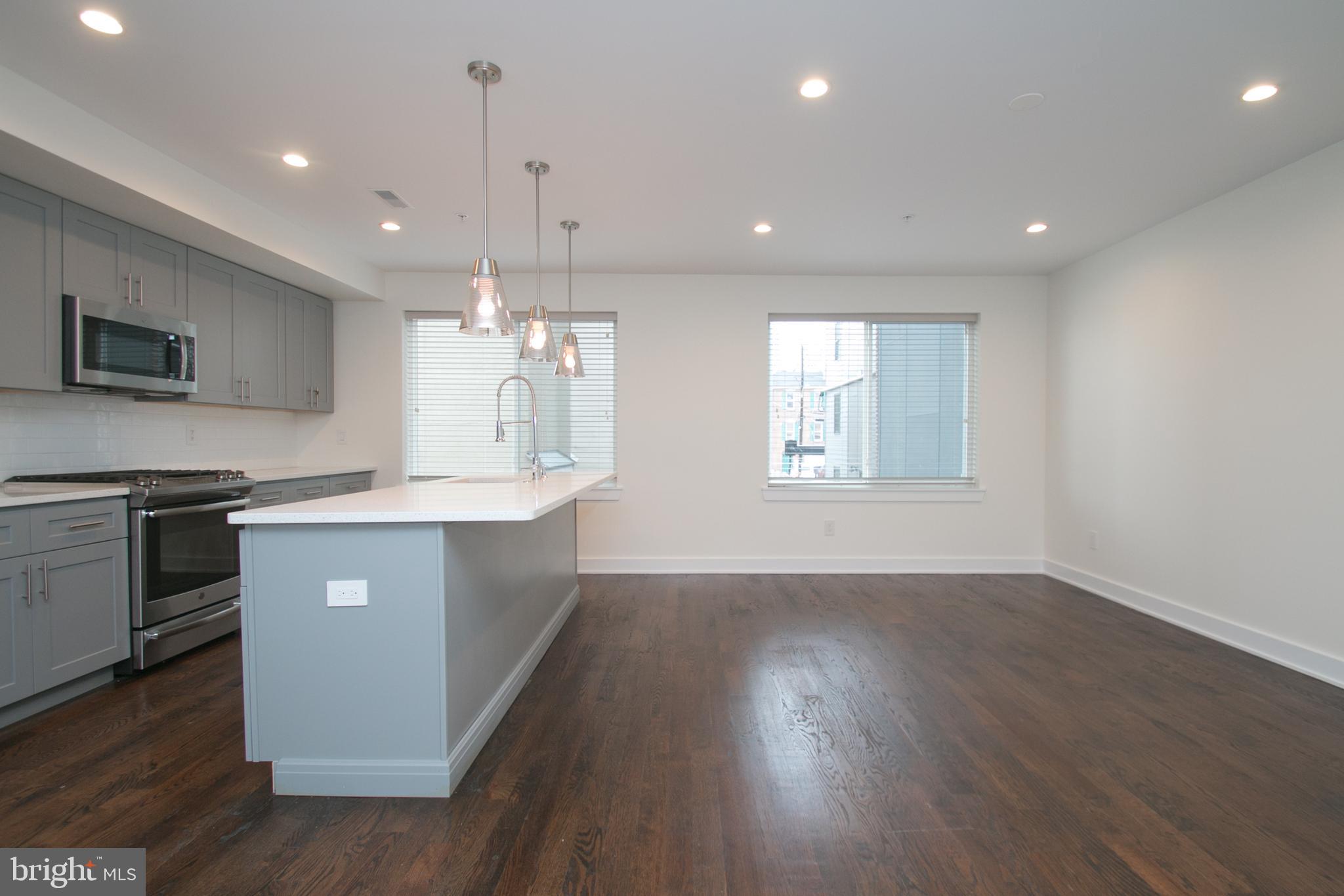 1022 South 2nd Street, Unit 4 Philadelphia, PA 19147 - Photo 11 of 50 a large kitchen with granite countertop a large counter top space a sink stainless steel appliances and a window