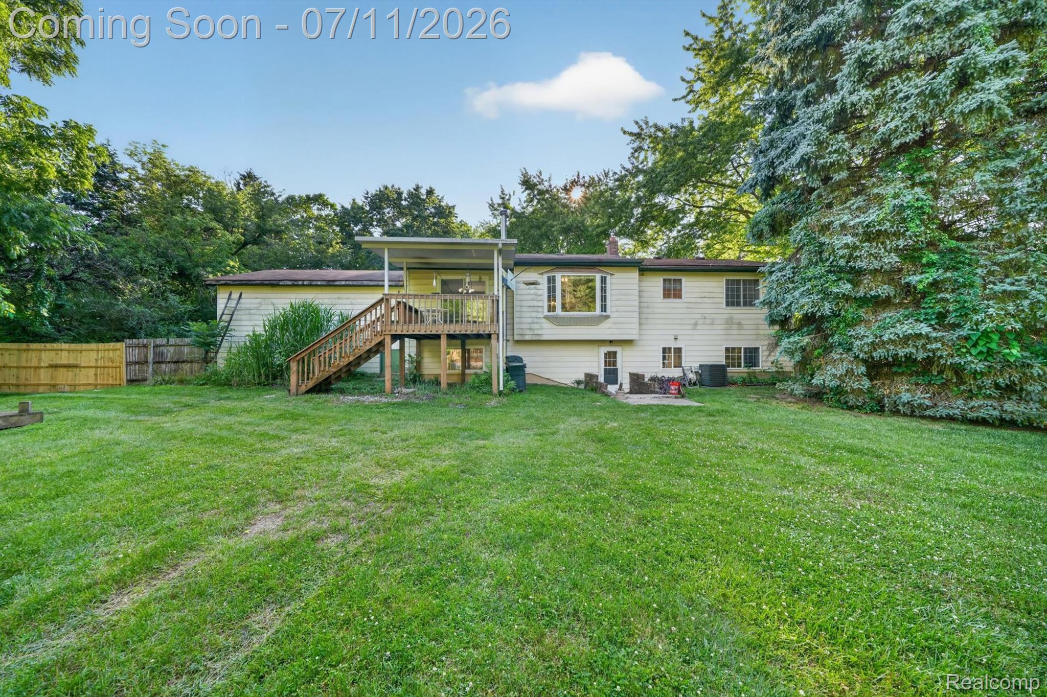4430 North Center Road Flint, MI 48506 - Photo 47 of 49 Expansive rear yard featuring a large wooden deck with stairs, a ground-level patio, and mature perimeter trees