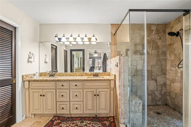 a bathroom with a granite countertop sink a mirror and a shower